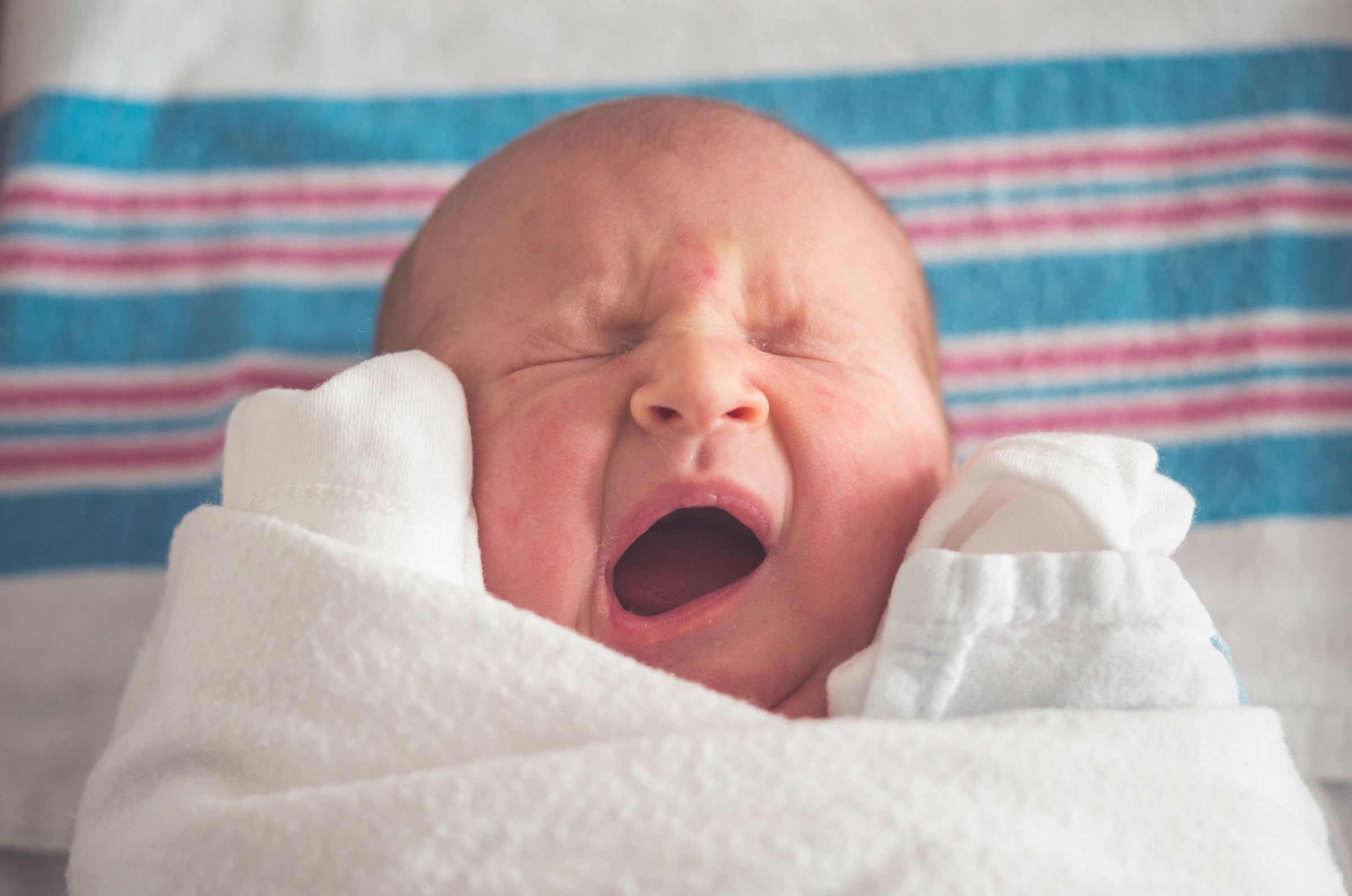 Newborn baby yawns in his crib