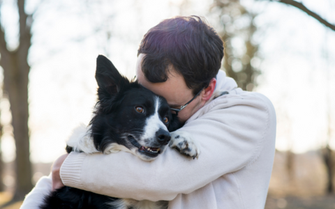 Guy embracing his dog as they bond with each other.