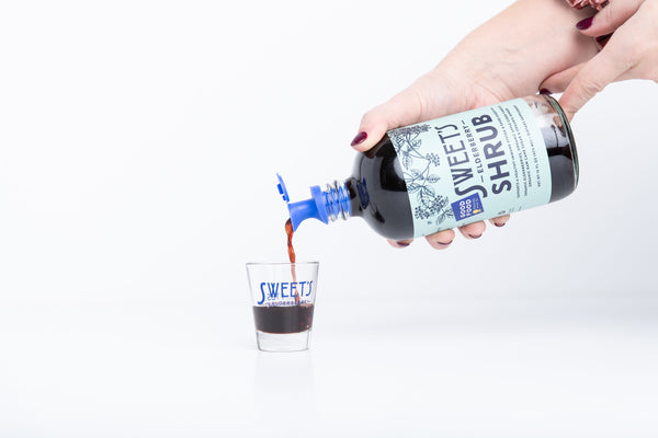 sweets elderberry shrub drinking vinegar being poured into a shot glass