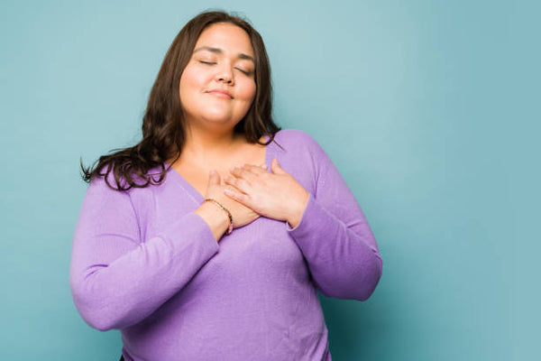 Woman with Dark Hair and Purple Sweater Holding Her Hands Over Her Heart