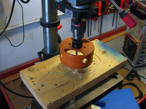 In this guide I'll be using my bench top drill press. Before making our 120mm hole, You'll want to find a piece of wood to place your panel upon, before using the hole saw. This will help prevent the top panel from bending and drilling into your work surface.