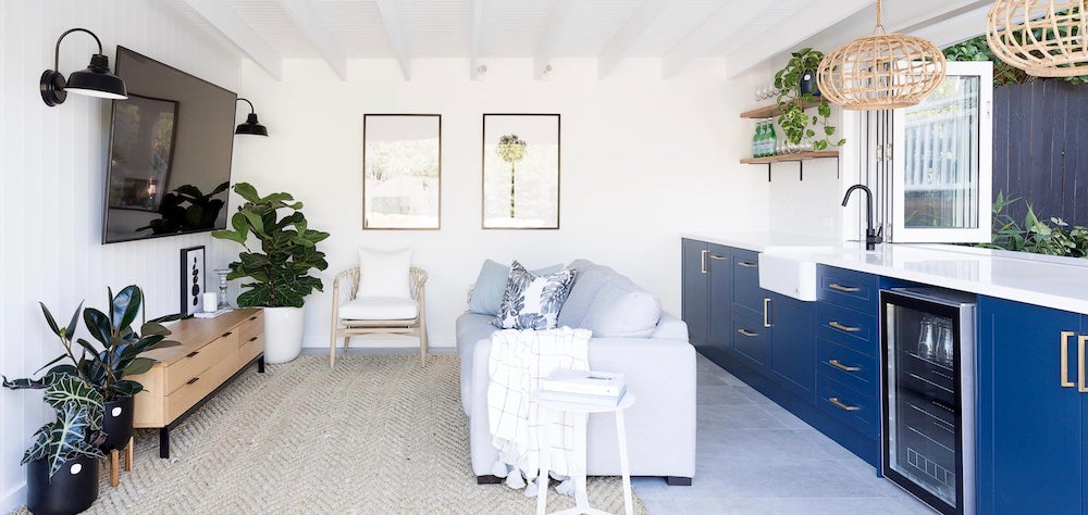 Blue, green and white were the answer when styling this soft grey sofa set against the deep blue cabinetry. Image: Heliconia / Simon Whitbread