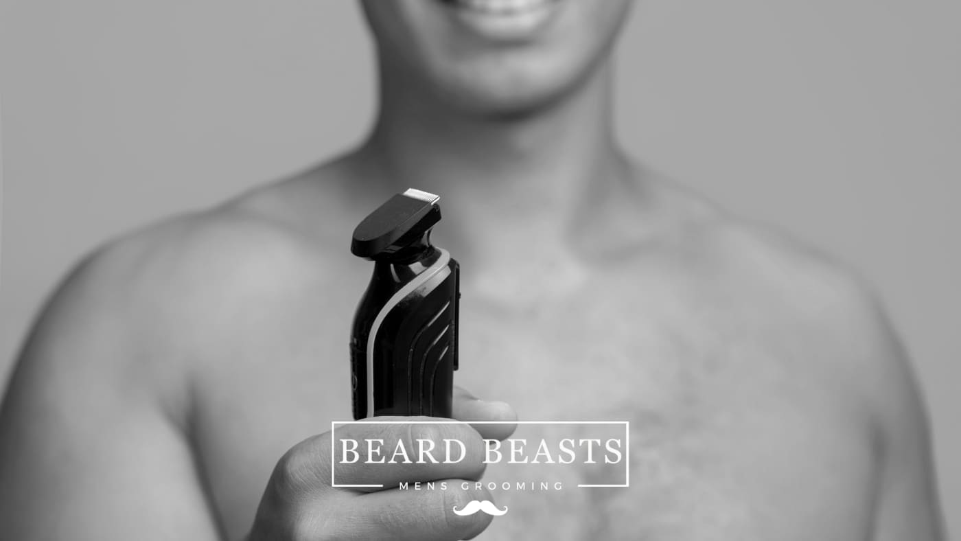 Man smiling while holding an electric trimmer, implying the start of a grooming routine highlighting the benefits of manscaping.