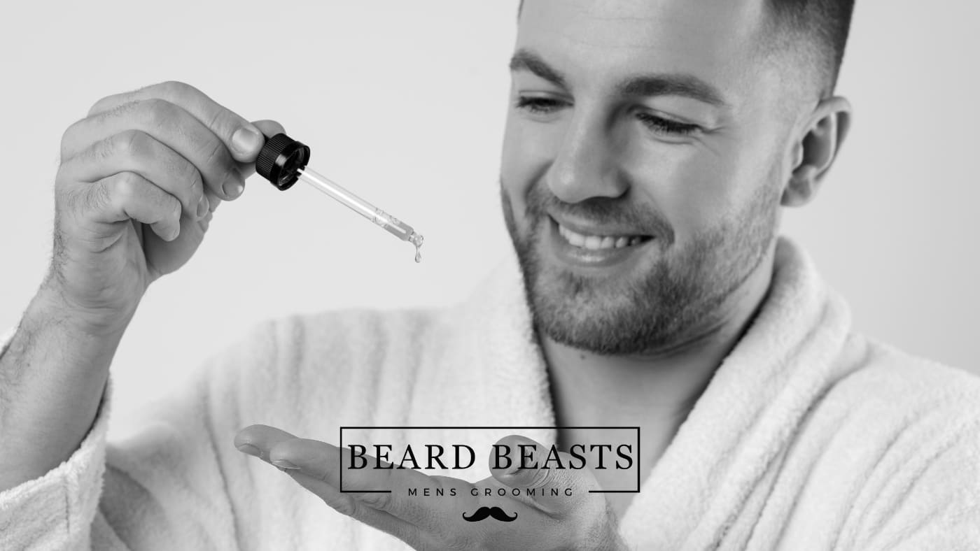 A man in a white bathrobe smiling while carefully dispensing beard oil from a dropper onto his hand, illustrating the process of how to use beard oil for grooming