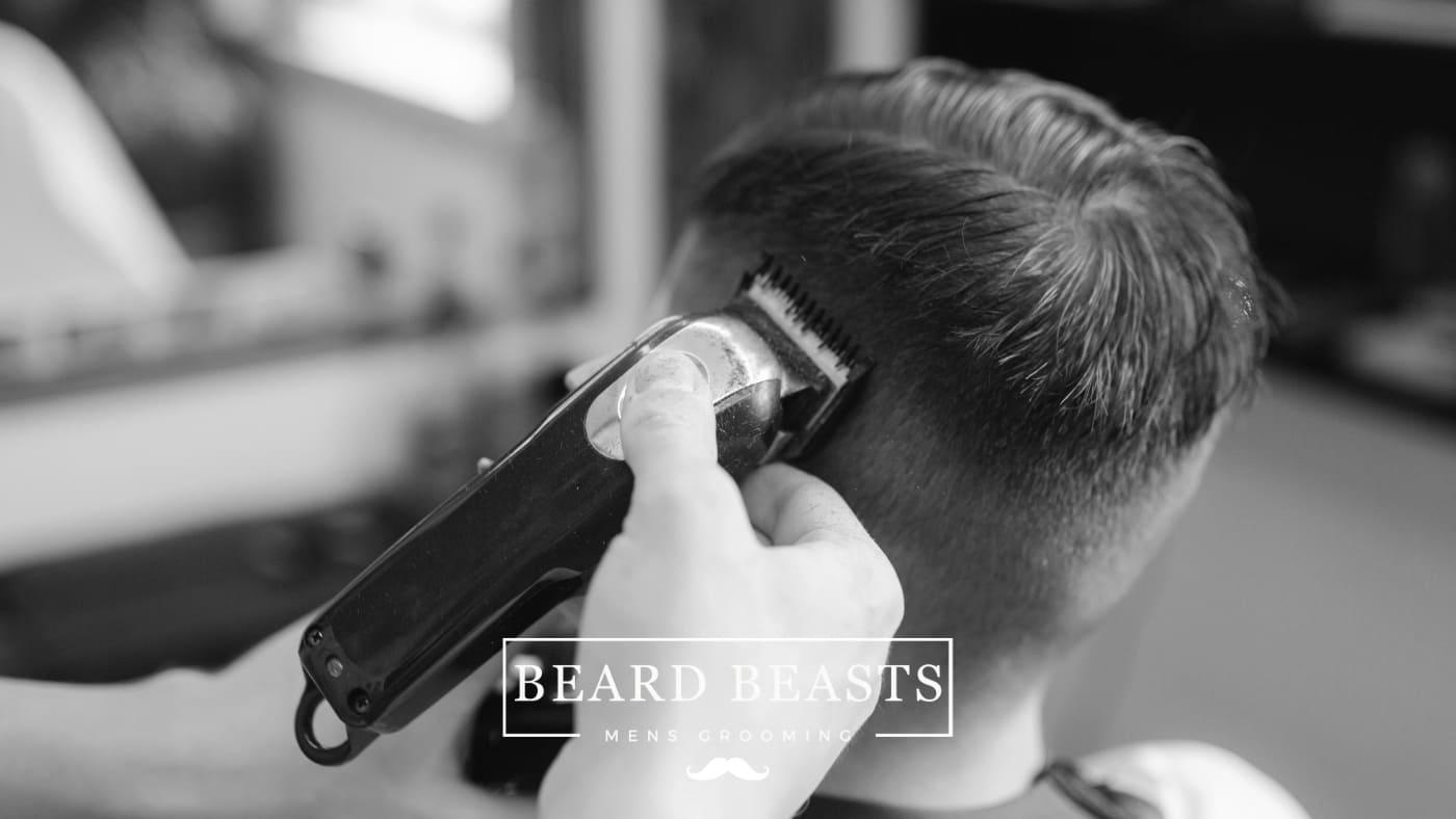 A barber crafting a fade haircut on a client, illustrating the technique of what is a fade haircut by blending the hair from a shorter length on the sides to a longer length on top