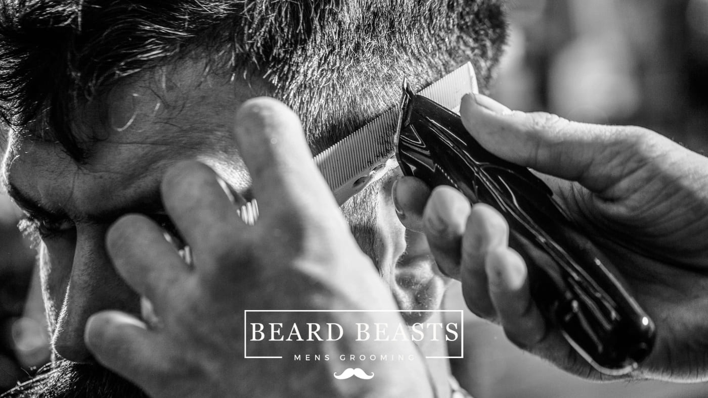 Barber carefully crafting a fade haircut with precision clippers - highlighting the art of fade vs skin fade techniques
