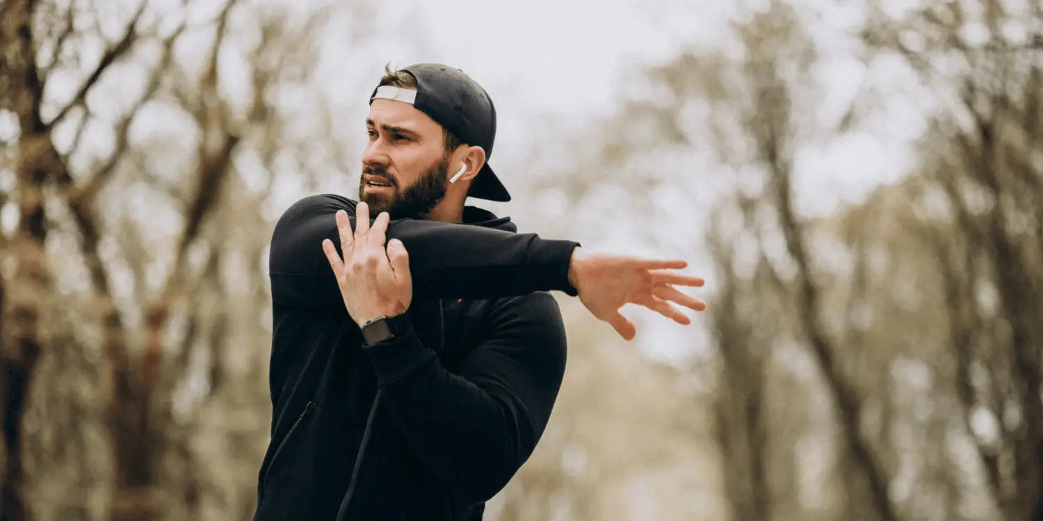 Image of a fit bearded man stretching his muscles outdoors, preparing for a morning run as part of his holistic approach to overcoming the 'my beard is patchy' challenge.