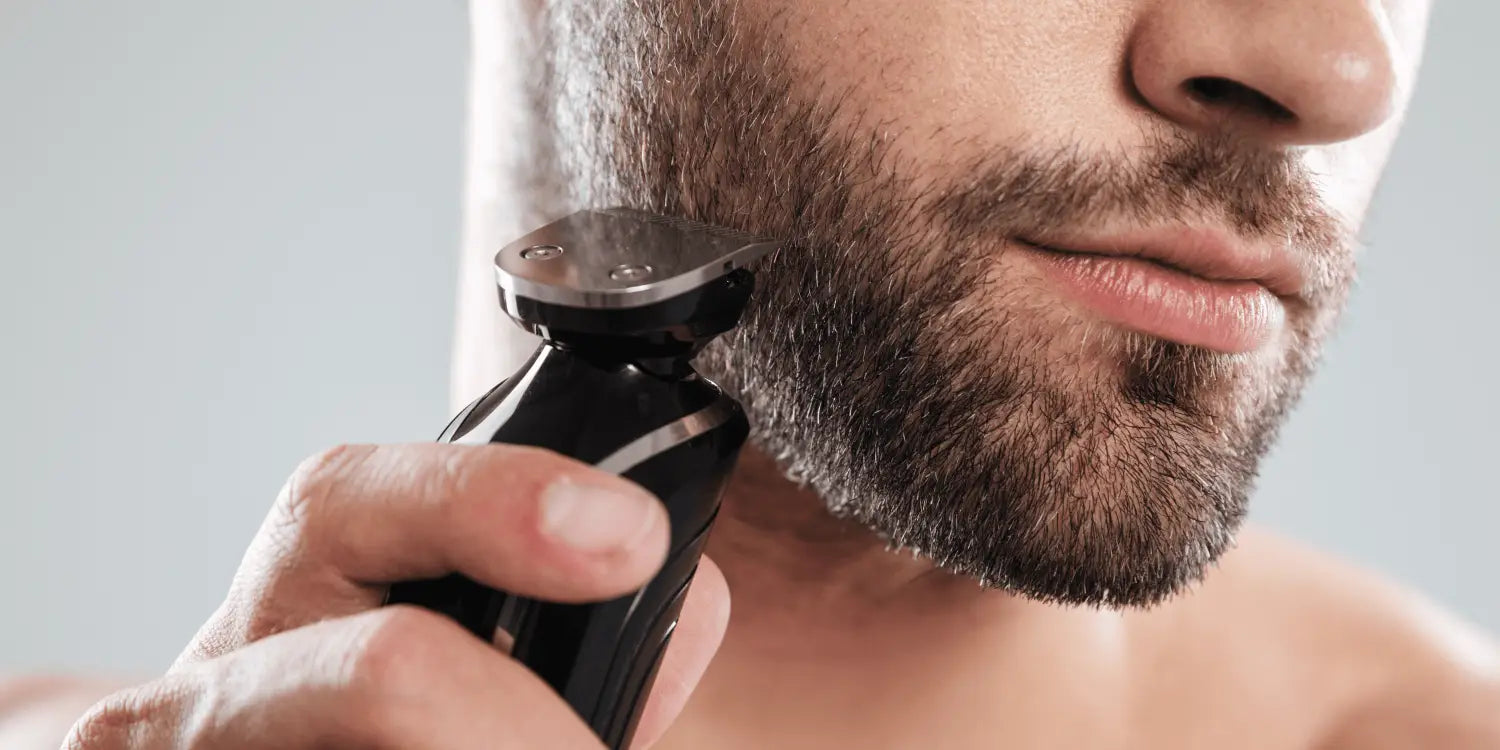 Man using a sharp-bladed beard trimmer to trim his beard for precise grooming