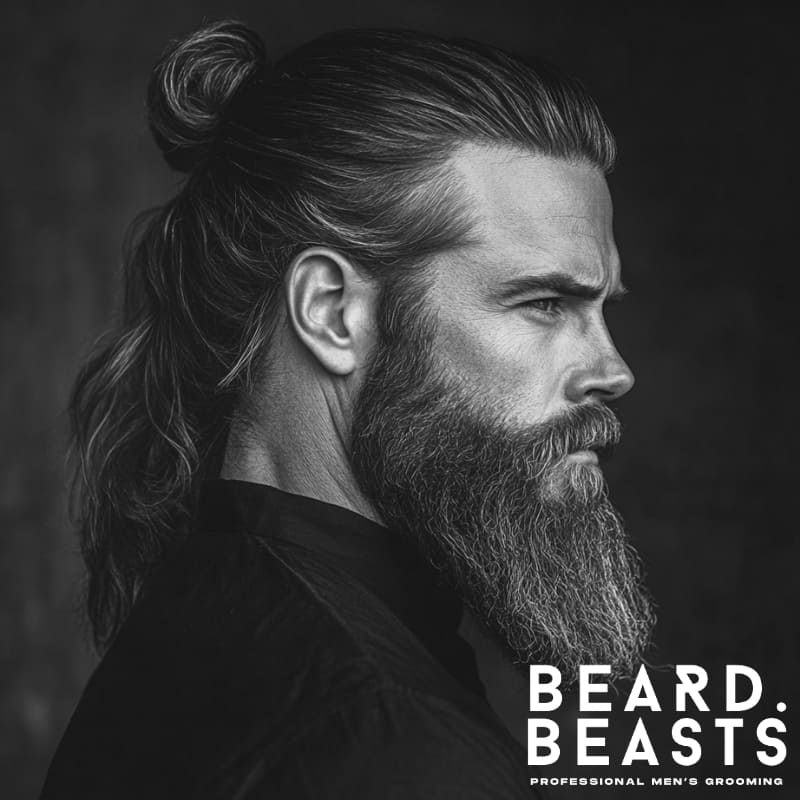 Profile of a man with a half-up hair tie and a full, well-groomed beard—combining structure, flow, and confident grooming.