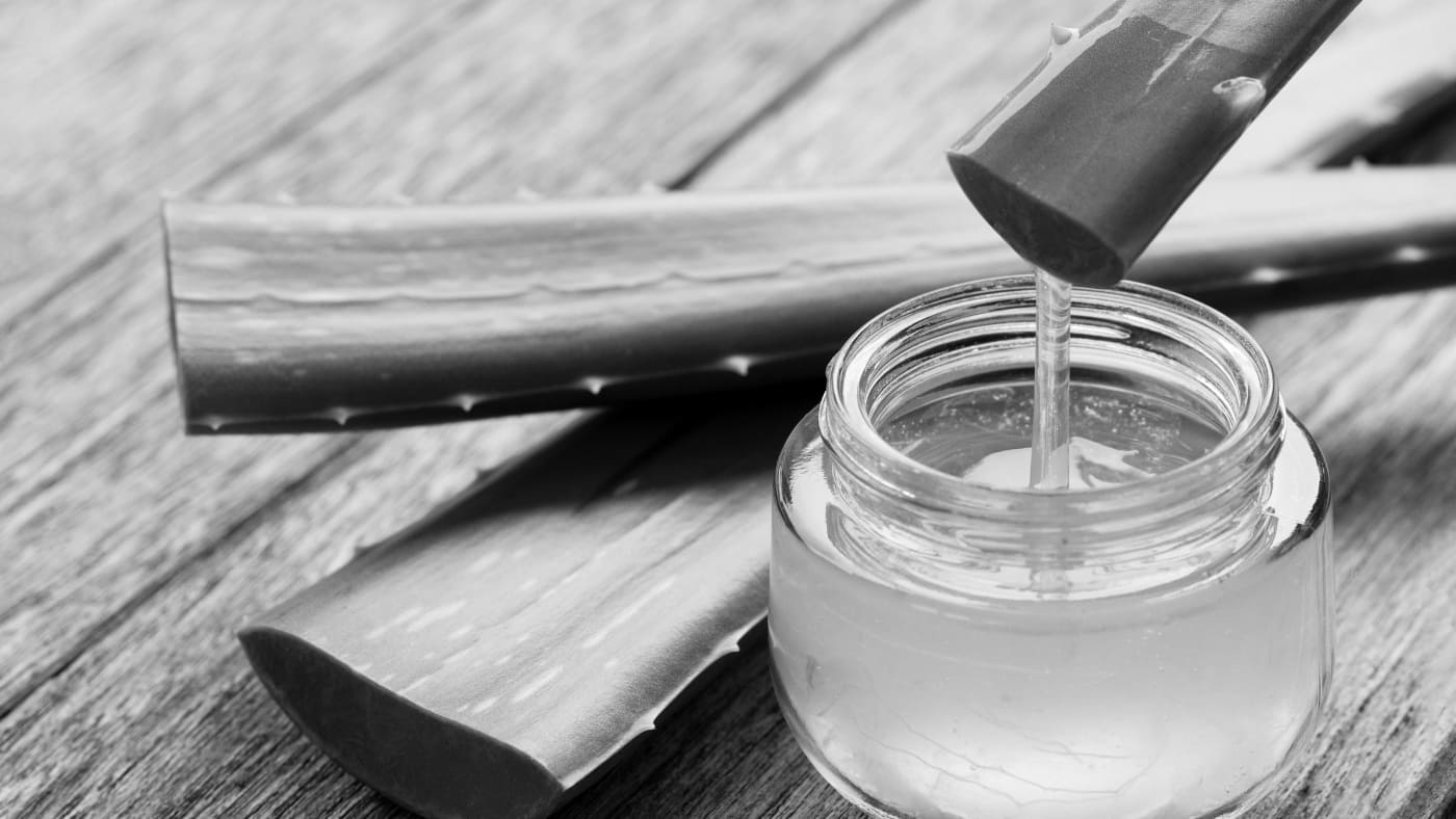 Jar of aloe vera gel with fresh aloe leaves, natural remedy for beard growth