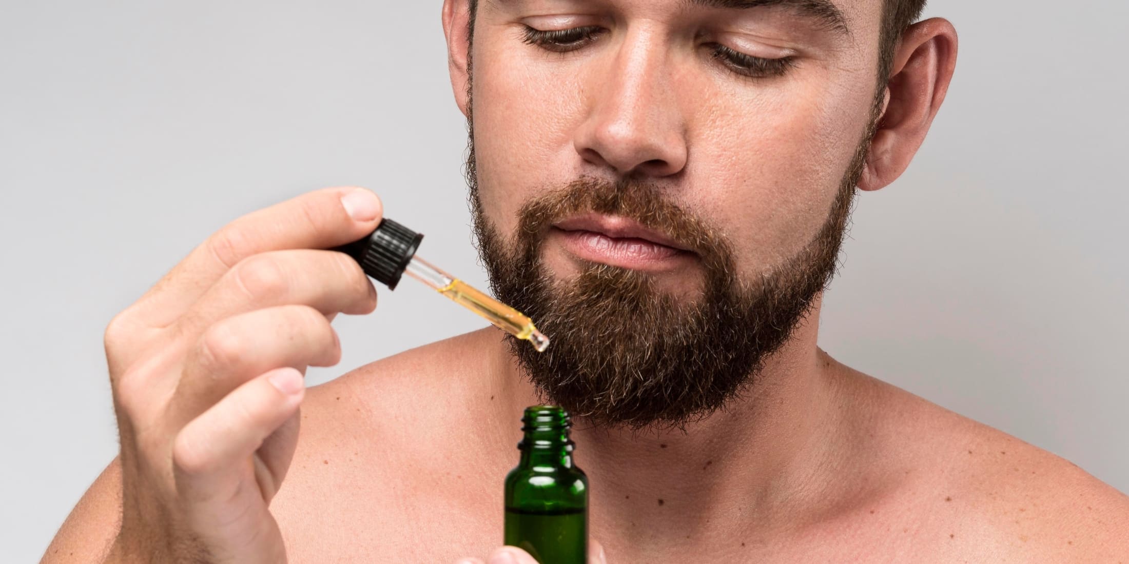 a man looking at his beard oil thinking does beard oil work or not.