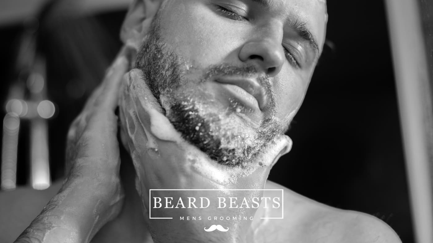 Man peacefully closes his eyes while thoroughly washing his beard with foam, demonstrating how to wash your beard