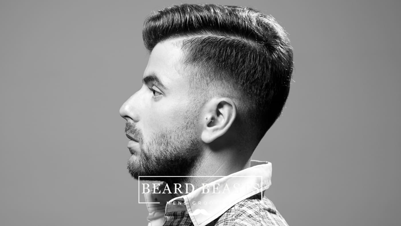 Side profile of a man with a well-groomed hairstyle that could be classified as a 'drop fade vs mid fade'