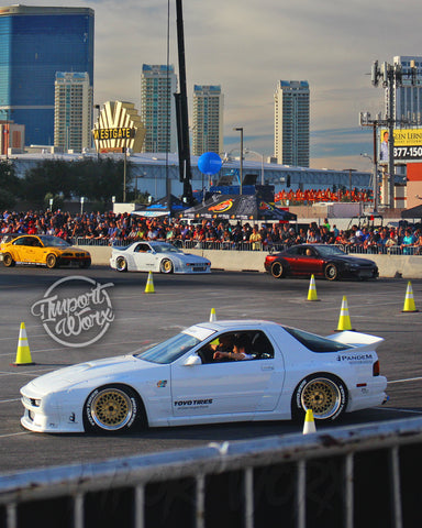 A white Rocket Bunny Mazda RX-7 with flared fenders and custom wheels on display at SEMA 2018.