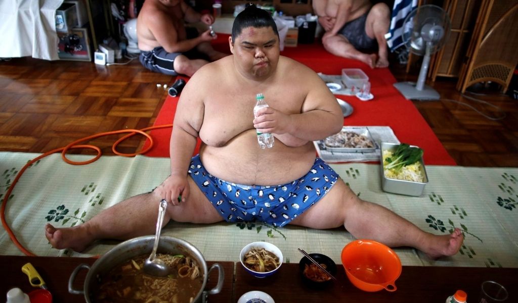 Lutteur de sumo assis par terre pour manger son repas