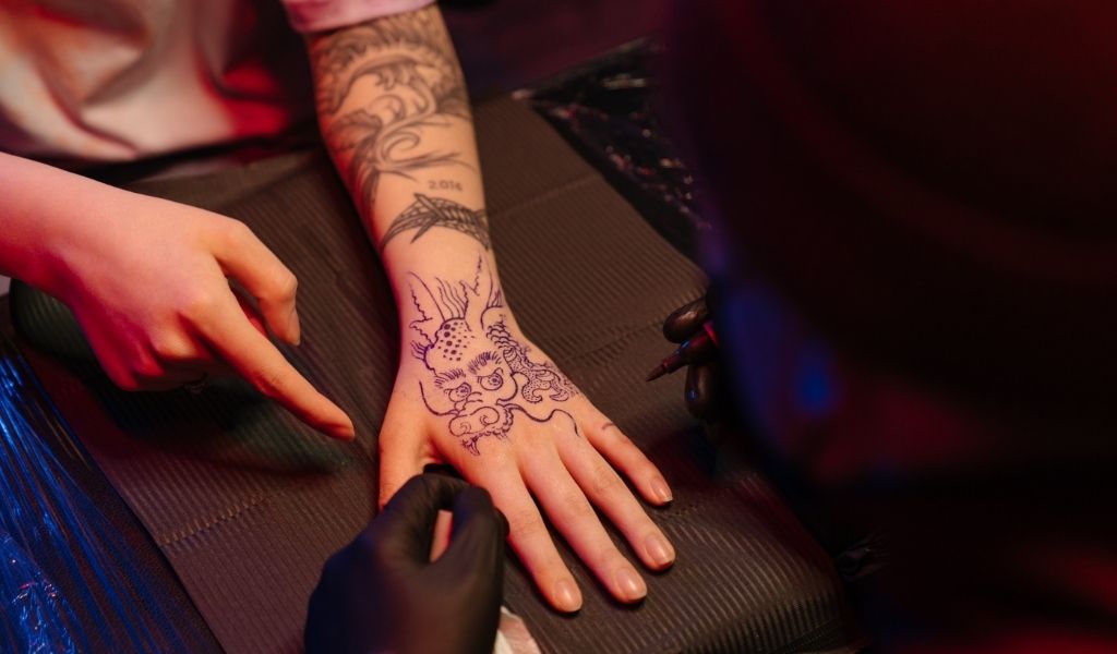 personne entrain de se faire tatouer un dragon japonais sur la main