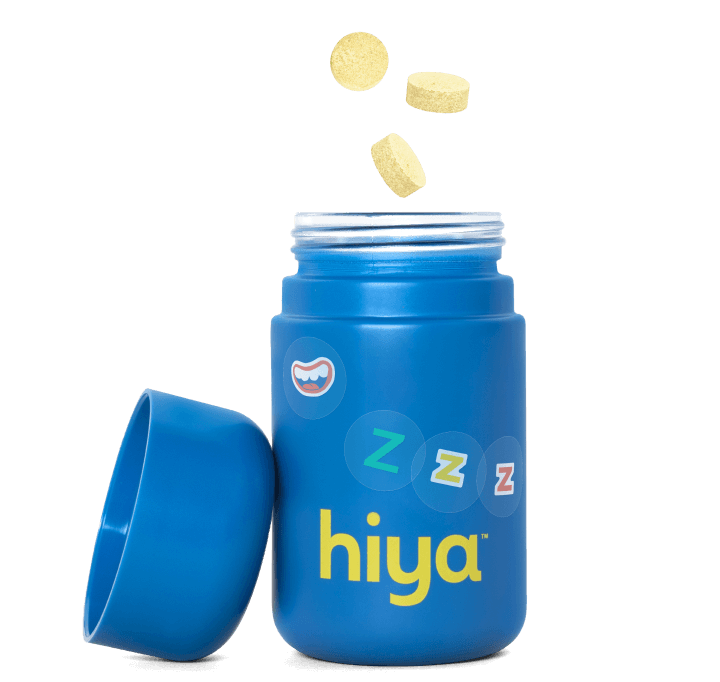 A bottle of Hiya Kids Bedtime Essentials decorated with stickers. It's lid is off and chewables are floating above it.