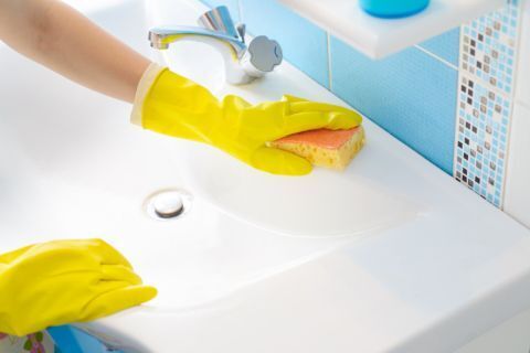 person scrubbing the bathroom sink to eliminate odor