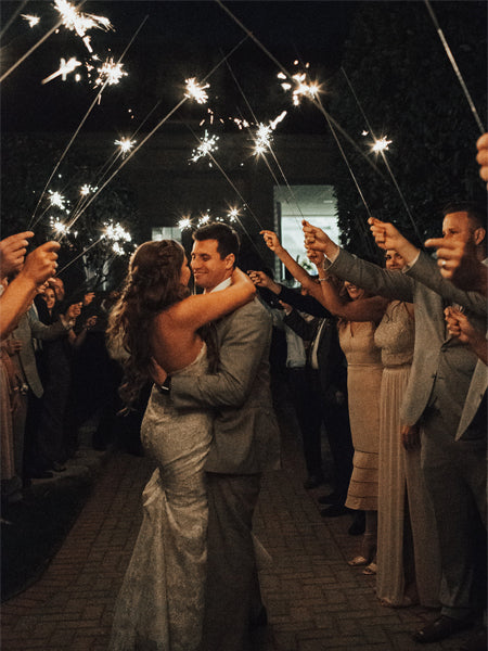 Couple standing under 36 inch sparklers while they are burning gold sparks