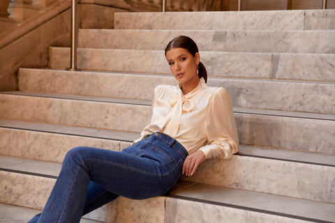 Woman wearing white shirt and denim jeans sitting on stairs