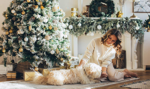 dog and woman sitting under Christmas tree