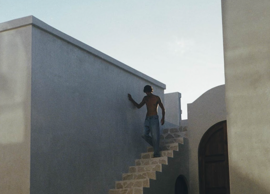 Image depicts person walking down rendered villa stairs, with a hand on the wall showing silver and gold jewellery.