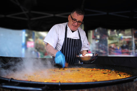 Hombre cocinando una paella. 