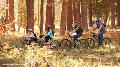 family of four has fun biking through woods near their off grid cabin