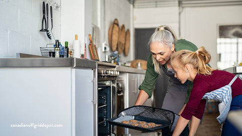 older woman and young girl put cookies in oven on off-grid range