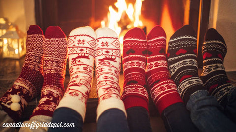 Four sets of feet in socks in front of cozy fire in off-grid cottage