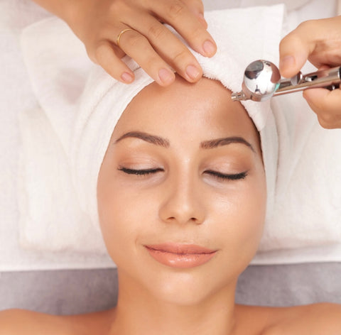 Woman is having airbrush onto face to hydrate her skin