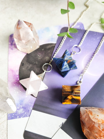 The Third Eye NZ - Merkaba Star Crystal Pendulums on tarot cards with plants and crystals surrounding