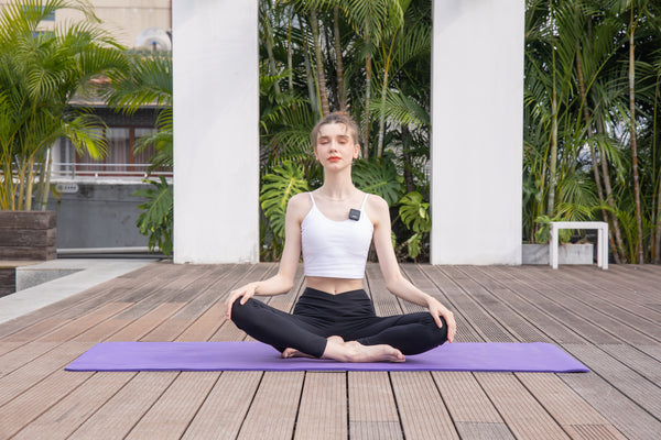 A woman wearing a Svantto wireless lavalier microphone is shooting a yoga video.