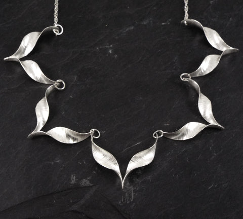 Silver necklace with five chevron shaped units linked in a row.