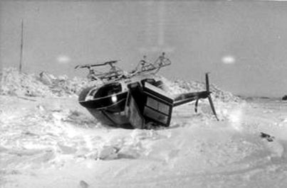 A helicopter laying upside down in a snow field after a white-out condition blinded the pilot.