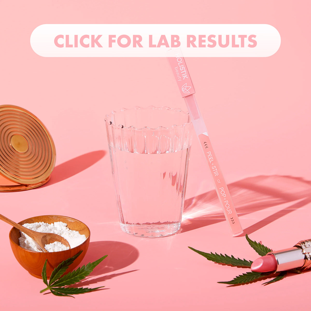 Lifestyle image of the HOLISTIK beauty STIK leaned up against a glass with some collagen in a bowl and a lipstick sitting on top of a hemp leaf