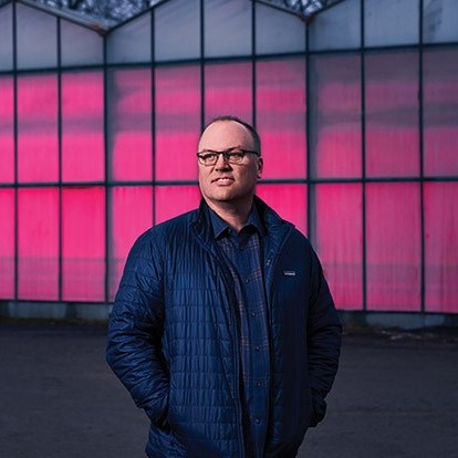 CEO of Wheatfield Gardens standing in front of their 200,000 sq. ft. greenhouse.