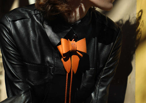 Marrs Makers bow amulet fashion jewelry in 'rough-out' saddle leather worn with Marrs Makers black leather Riding Blouse on model in West Village NYC 