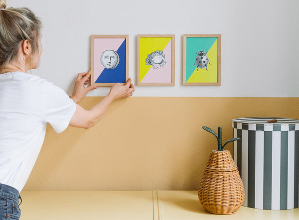 Woman putting colorful art prints on the wall