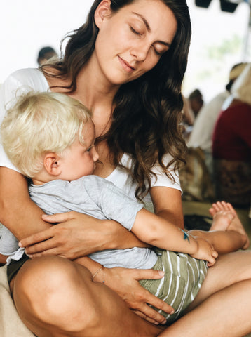 Mother sitting cross legged and cradling young boy in her lap