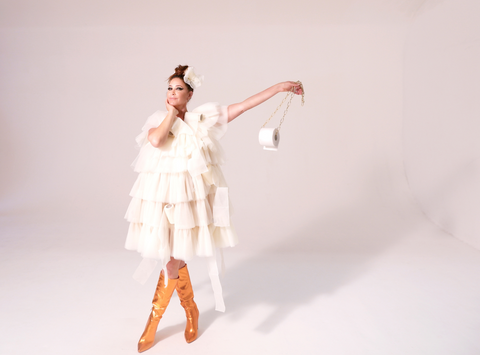 Lisa Snowdon wearing a dress made of toilet paper known as the loo roll dress while holding a toilet roll, in Symprove's latest fashion campaign on how to dress with gut issues