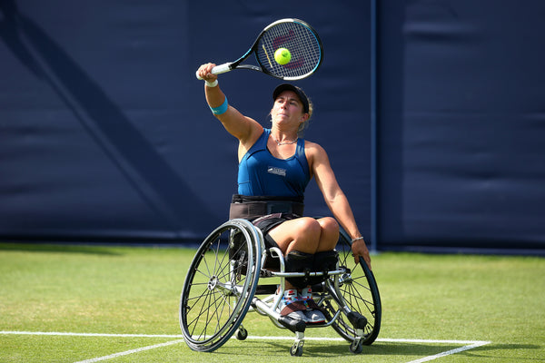 An image of Lucy Shuker playing tennis and hitting the ball with her racket. 