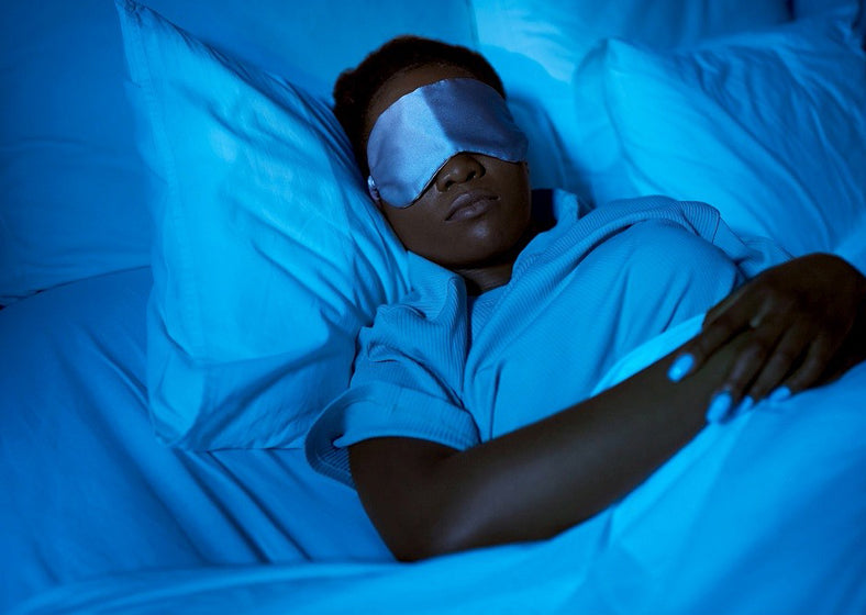 woman in eye mask sleeping in bed at home at night