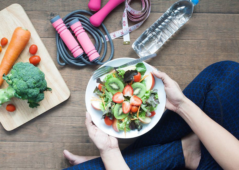 woman holding a dish of fresh salad with strawberries and kiwi