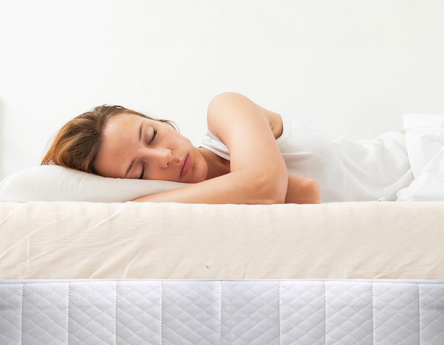 Person sleeping comfortably on a mattress with a thick topper and breathable organic cotton cover from Turmerry