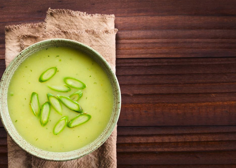 green asparagus soup in a bowl, garnished with sliced asparagus on top