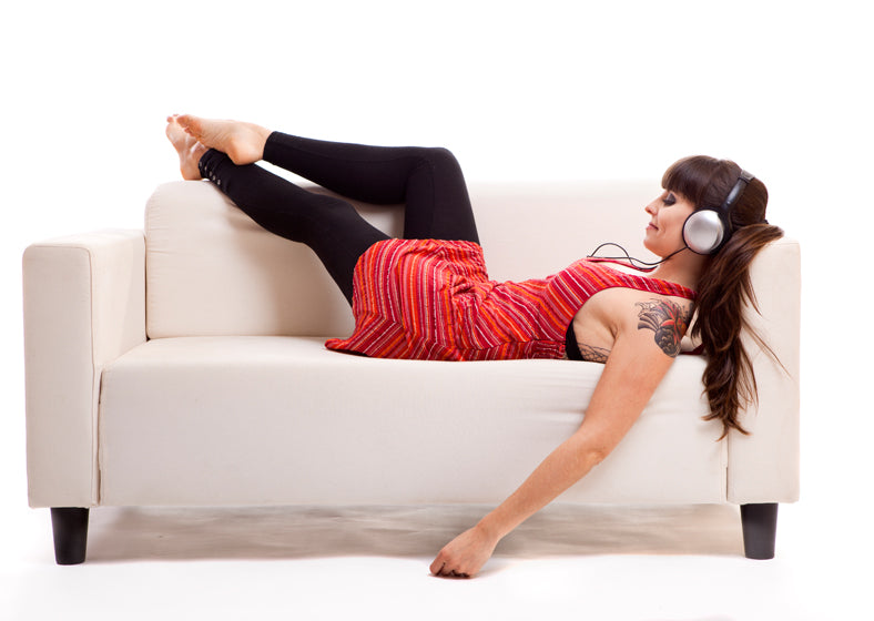 a woman lying on the sofa and listen to music with headphones