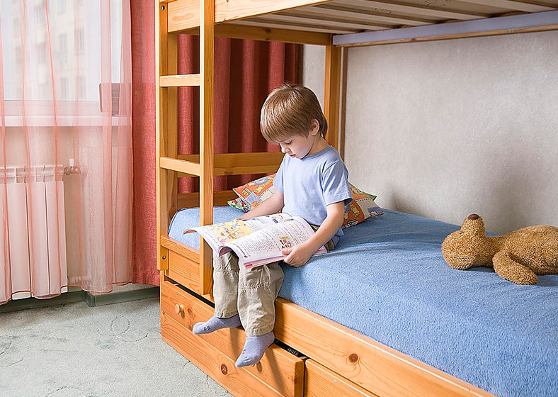 a kid sits on bunk bed reading a book
