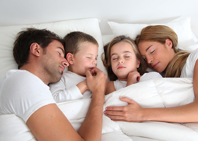 a family of 4 sleeping on a king size mattress