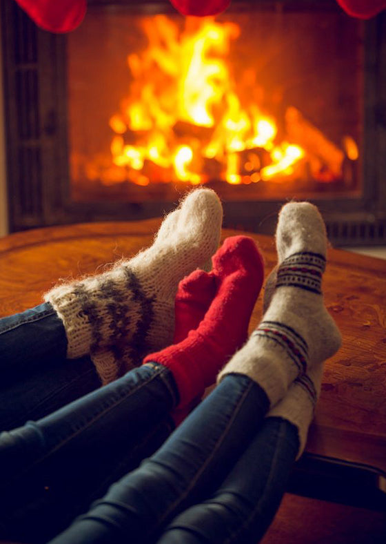 feet in woolen socks warming at a burning fireplace at house